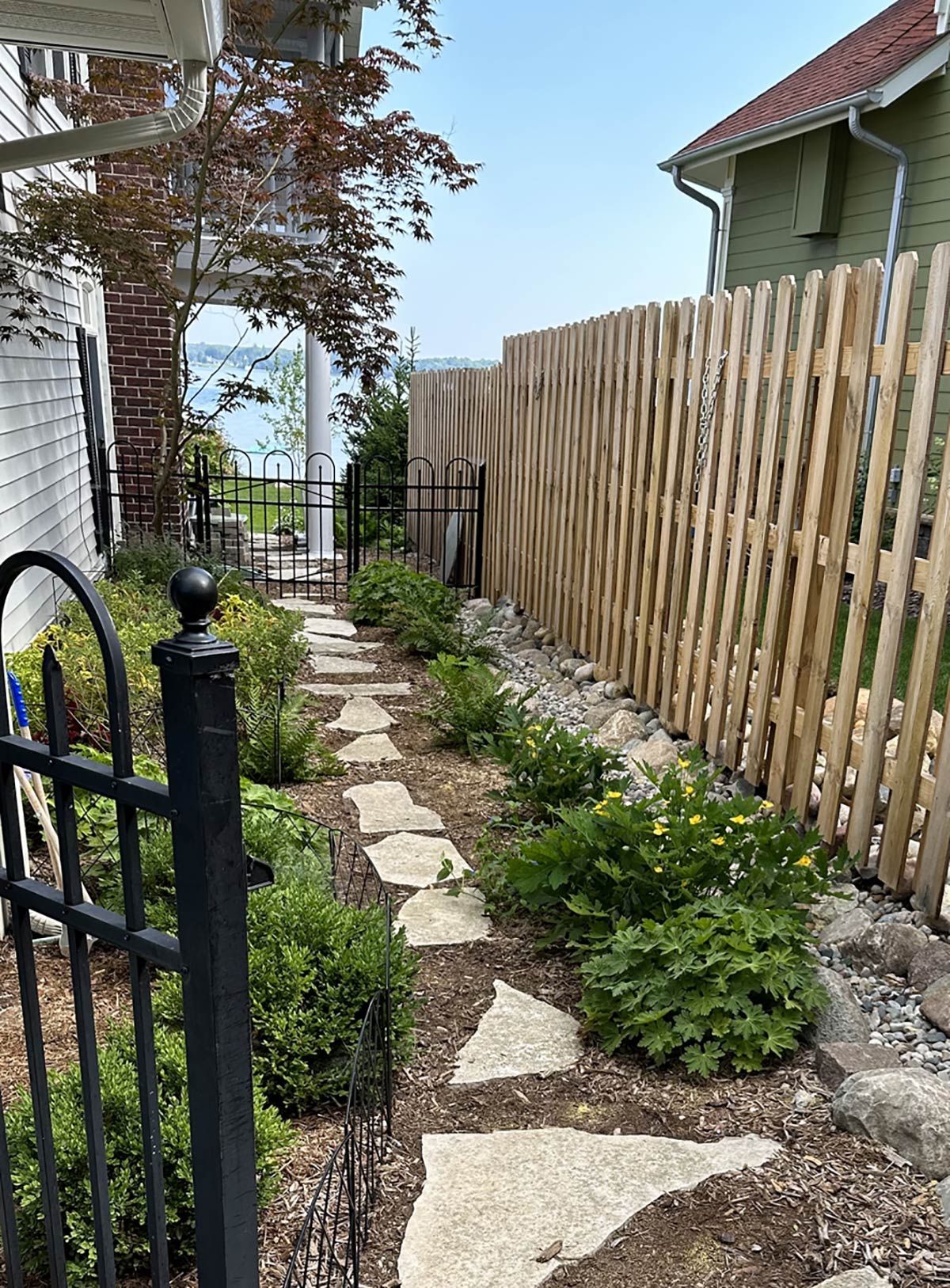 stone walkway between plantings with gate and privacy fence
