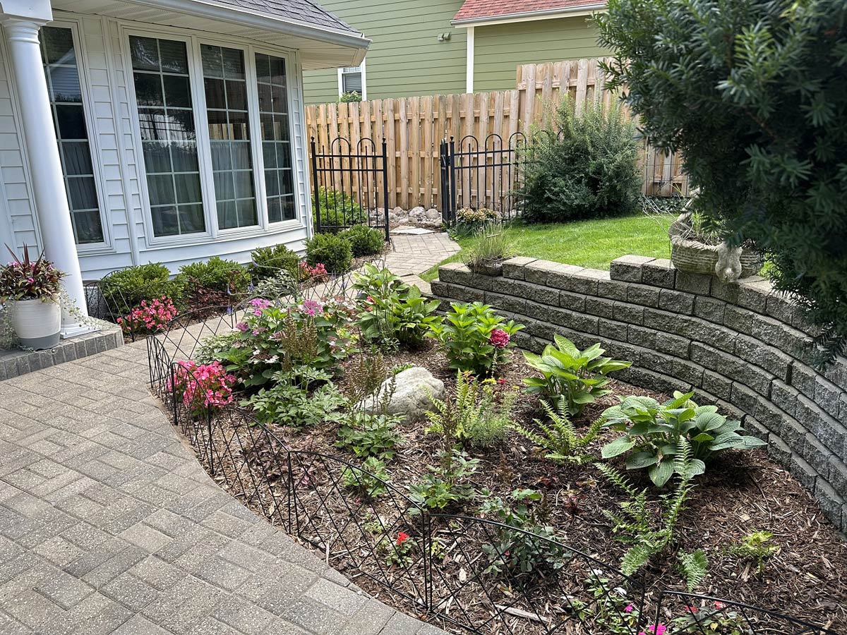 plantings between patio and retaining wall with home in background